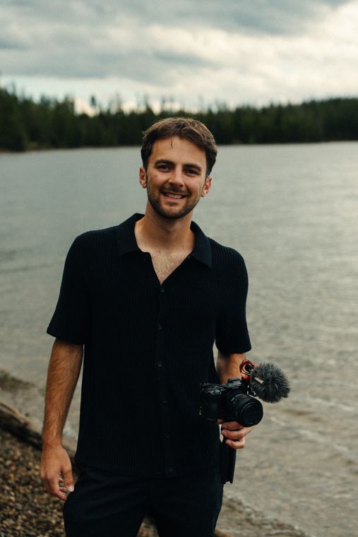 Trace Keller holding a video camera by a lake