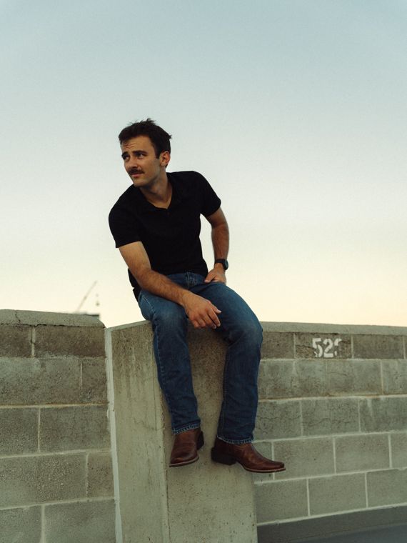 Trace Keller sitting on a downtown Boise rooftop wall at dusk