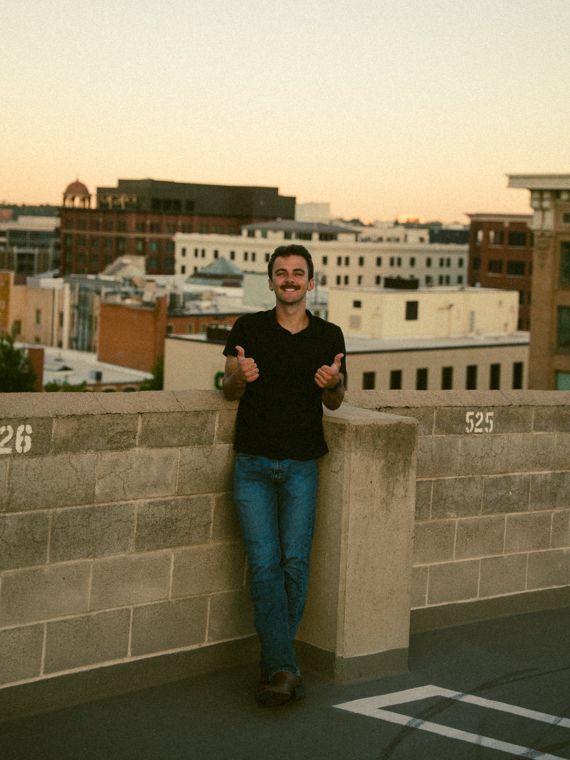Trace Keller giving a thumbs up on a Boise rooftop at sunset