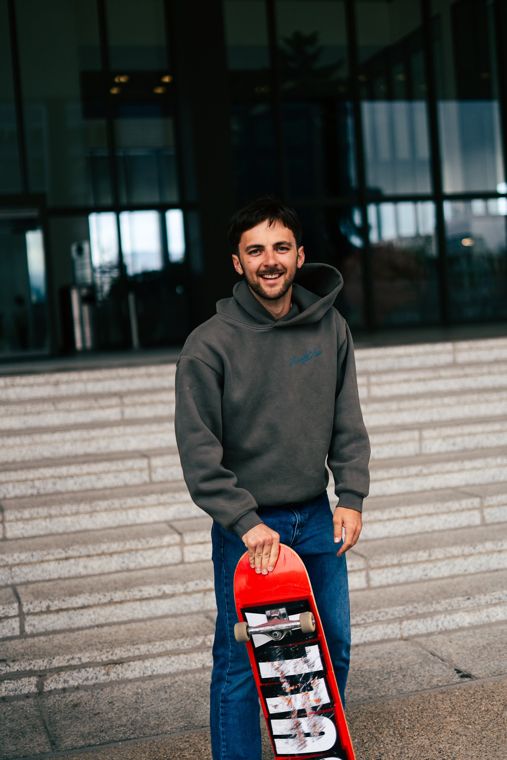 Trace Keller holding a red skateboard on city steps