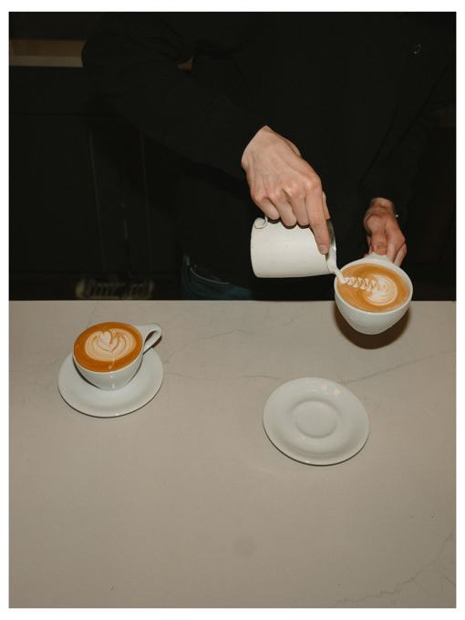 Barista pouring latte art into a cup on a marble counter