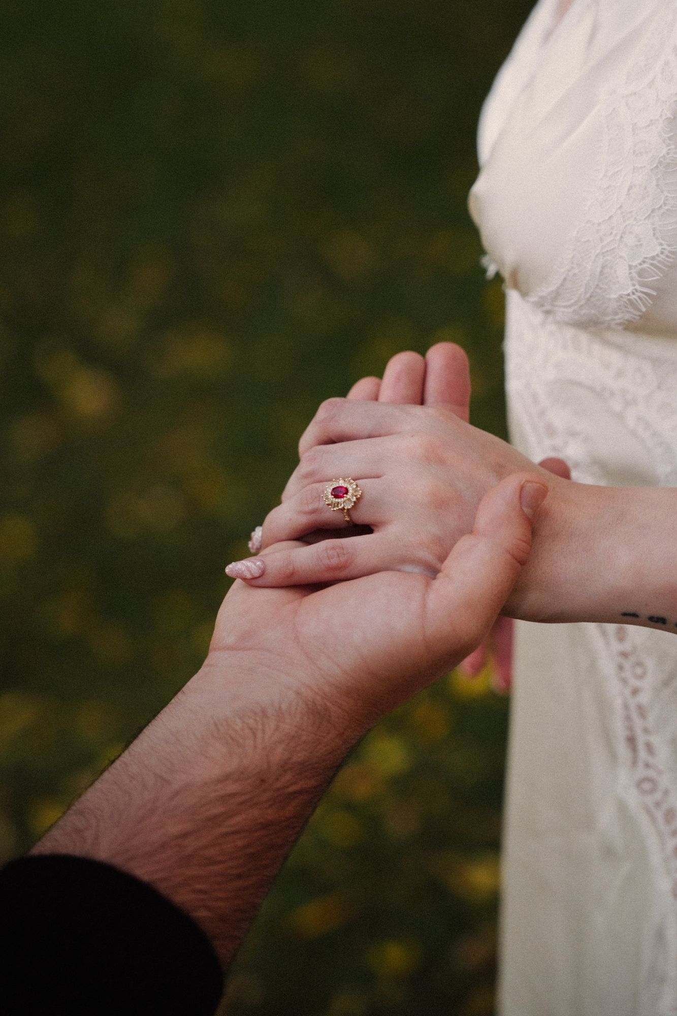 Close-up of James holding Cora's hand, with her ruby and diamond ring