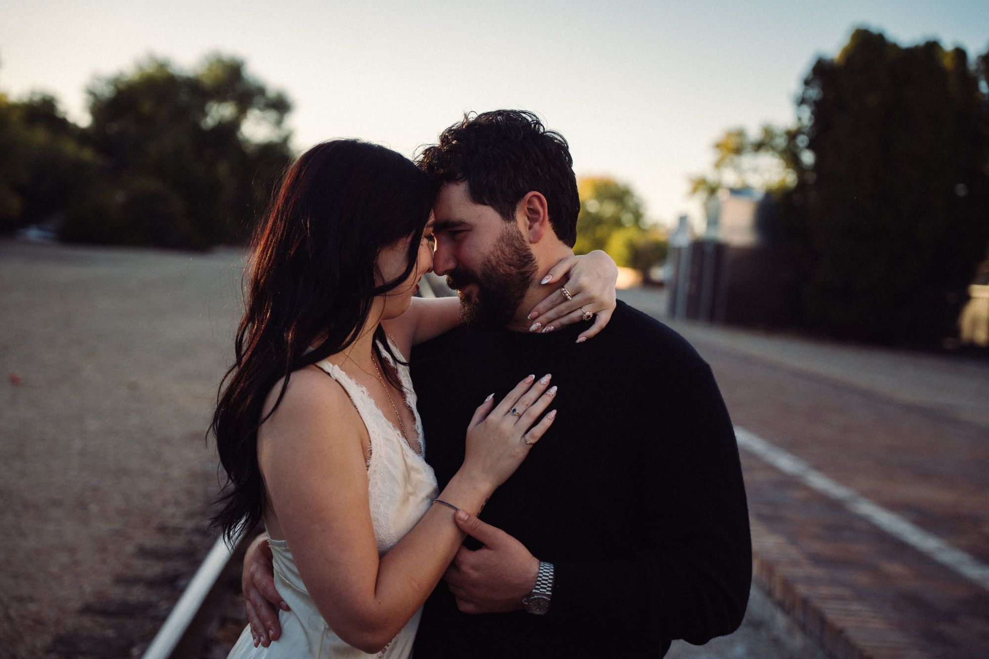 James and Cora touch foreheads at golden hour beside the railroad tracks near the Boise Depot