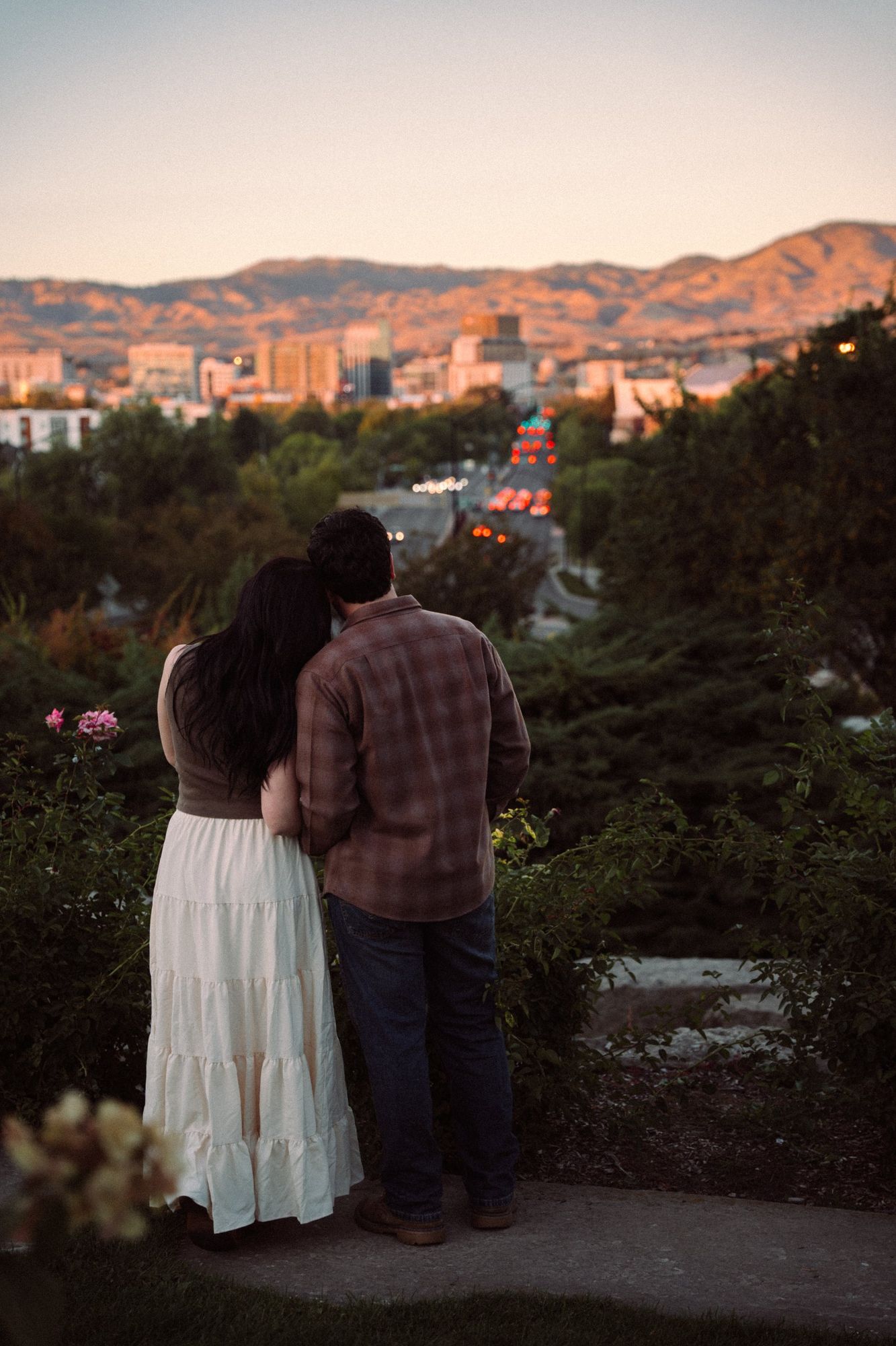 James and Cora from behind, leaning together and looking down the street toward downtown Boise and the foothills