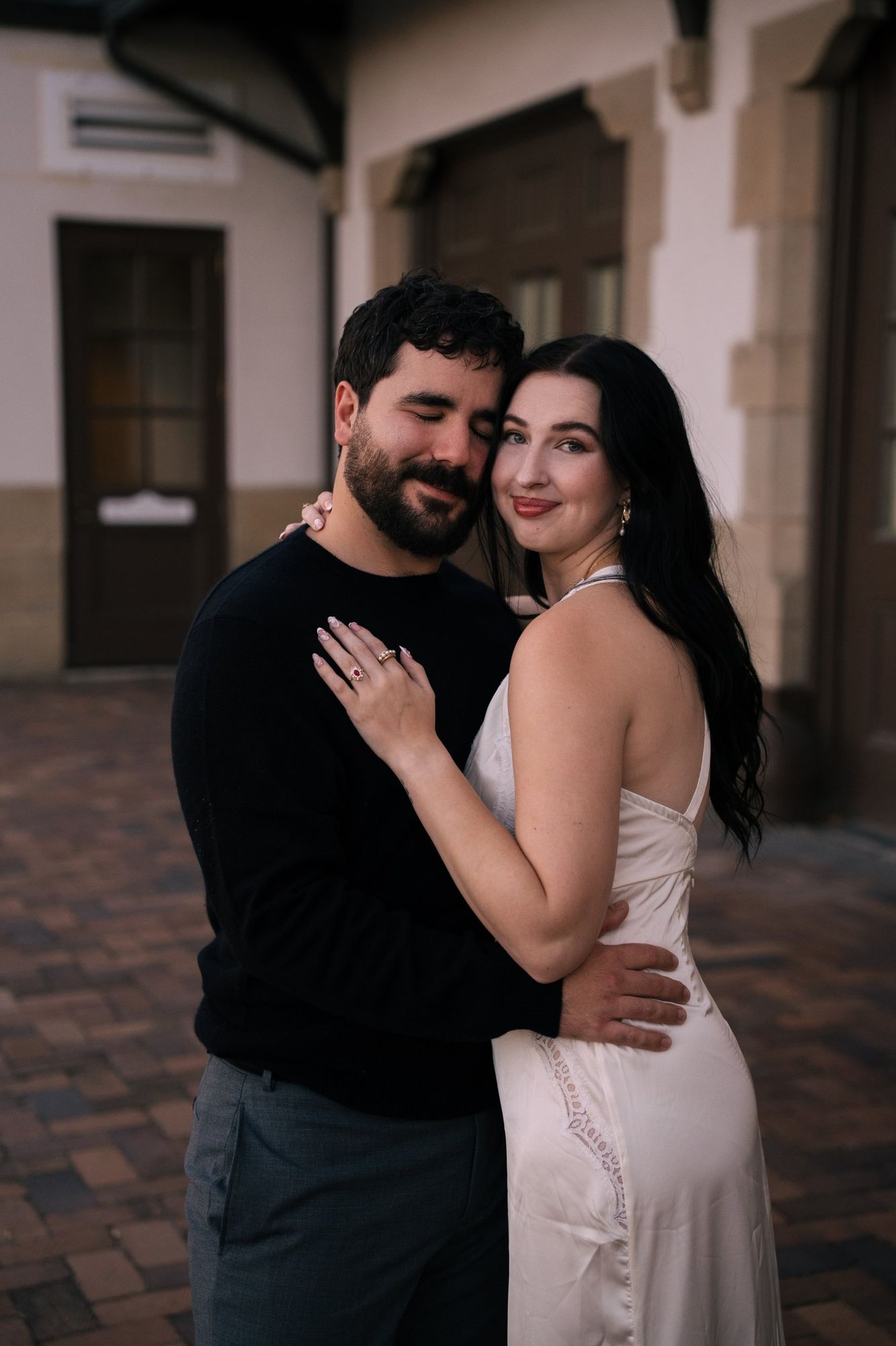 James and Cora embrace in the Boise Depot courtyard, his eyes closed and her smiling at the camera