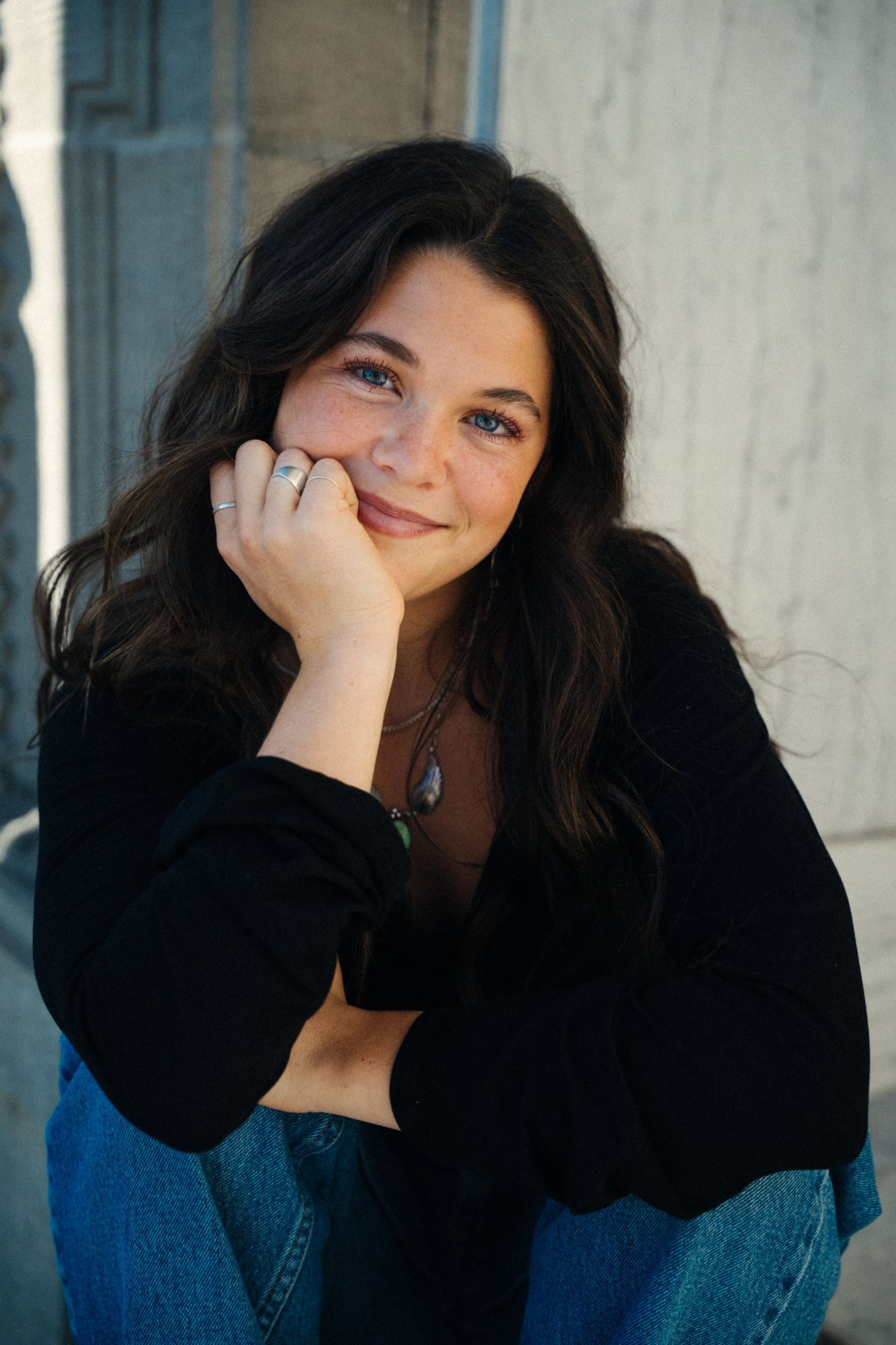 Close portrait of Adeline with her hand on her cheek, smiling at the camera with blue eyes