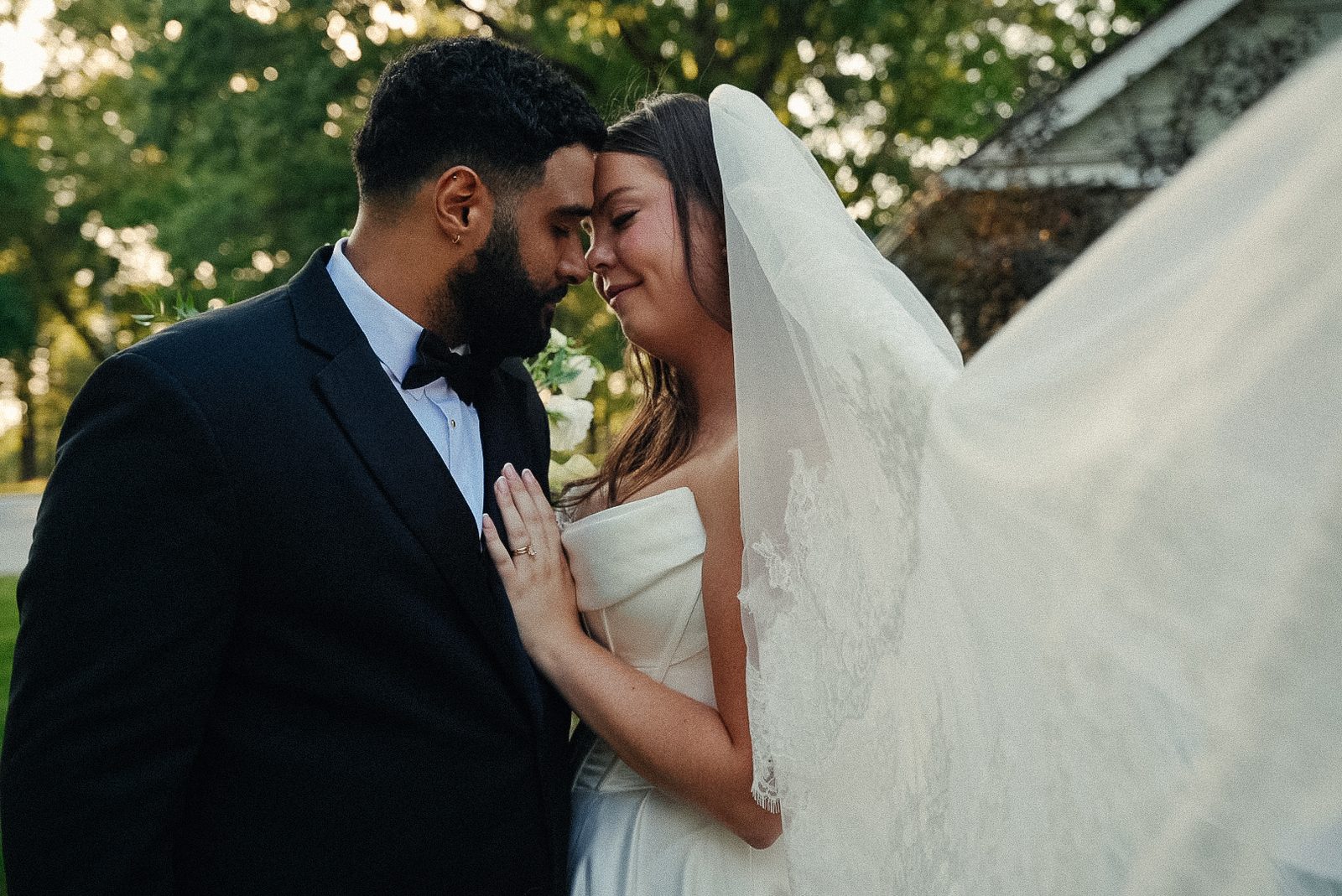 Caio and Trinity touching foreheads, her veil blowing in the golden evening light, her hand on his lapel