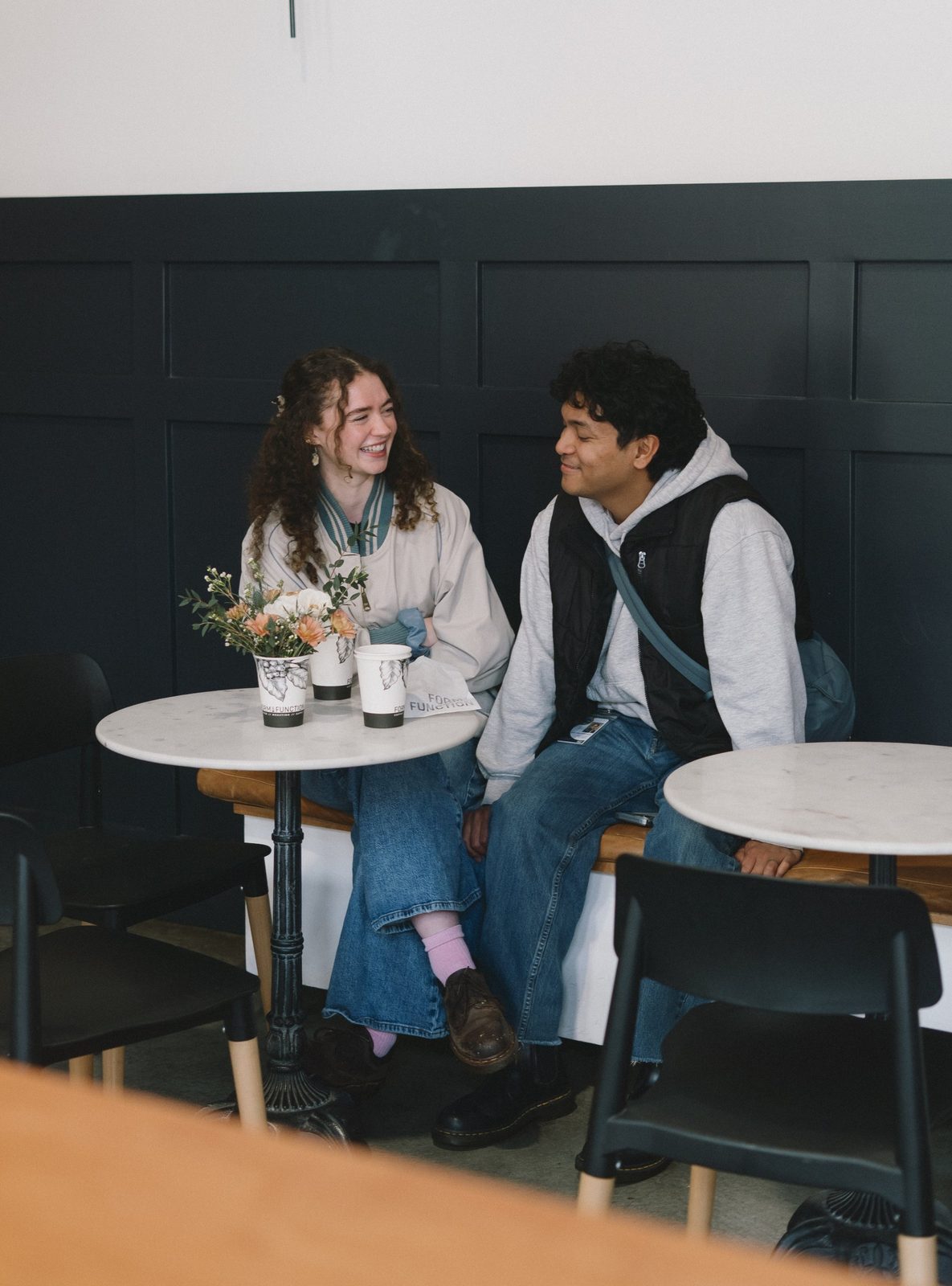 A couple laughing together at a marble table with Form & Function cups and a small bouquet