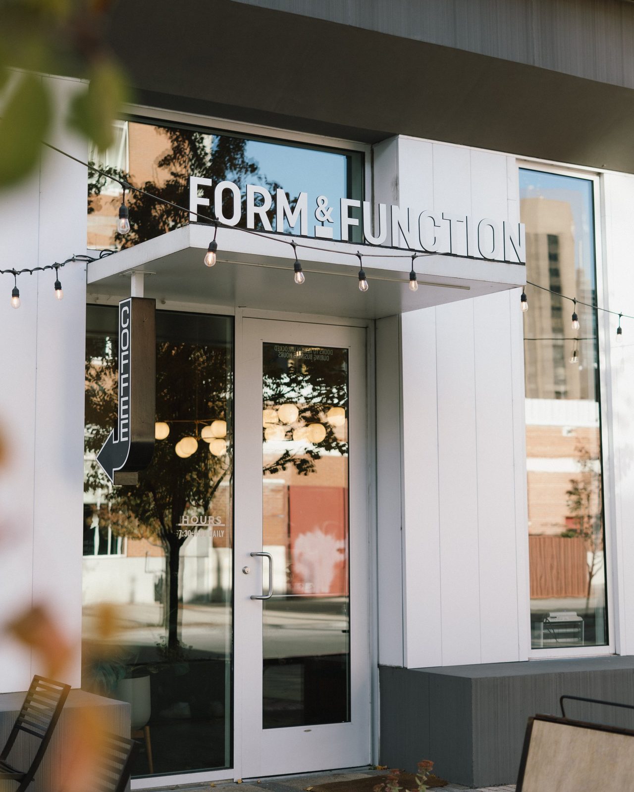 Form & Function storefront entrance with string lights and a hanging coffee arrow sign