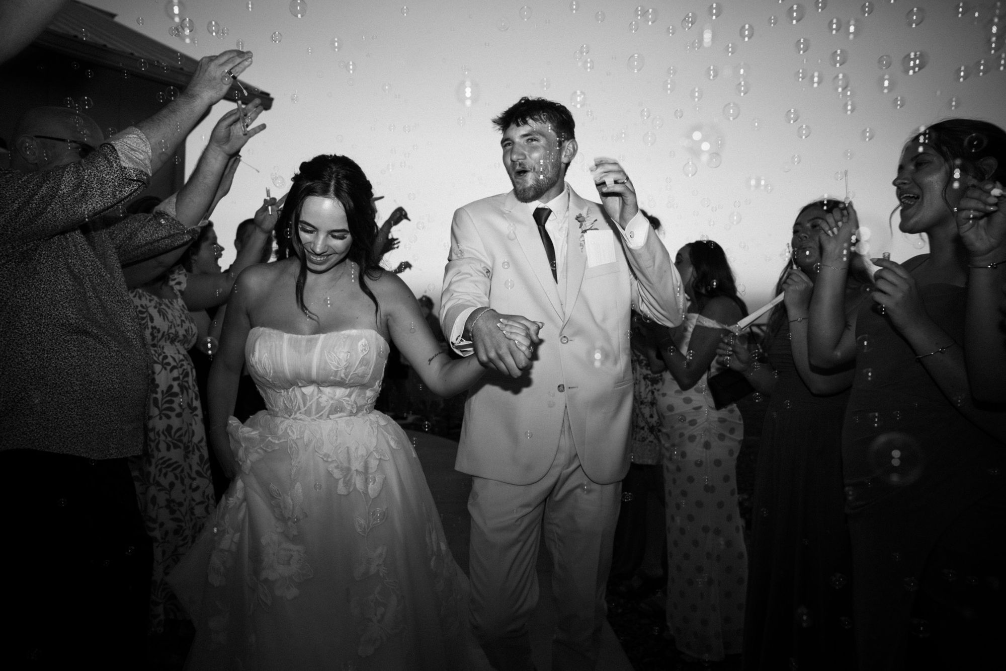 Black and white photo of a couple running through a bubble send-off at their Idaho wedding