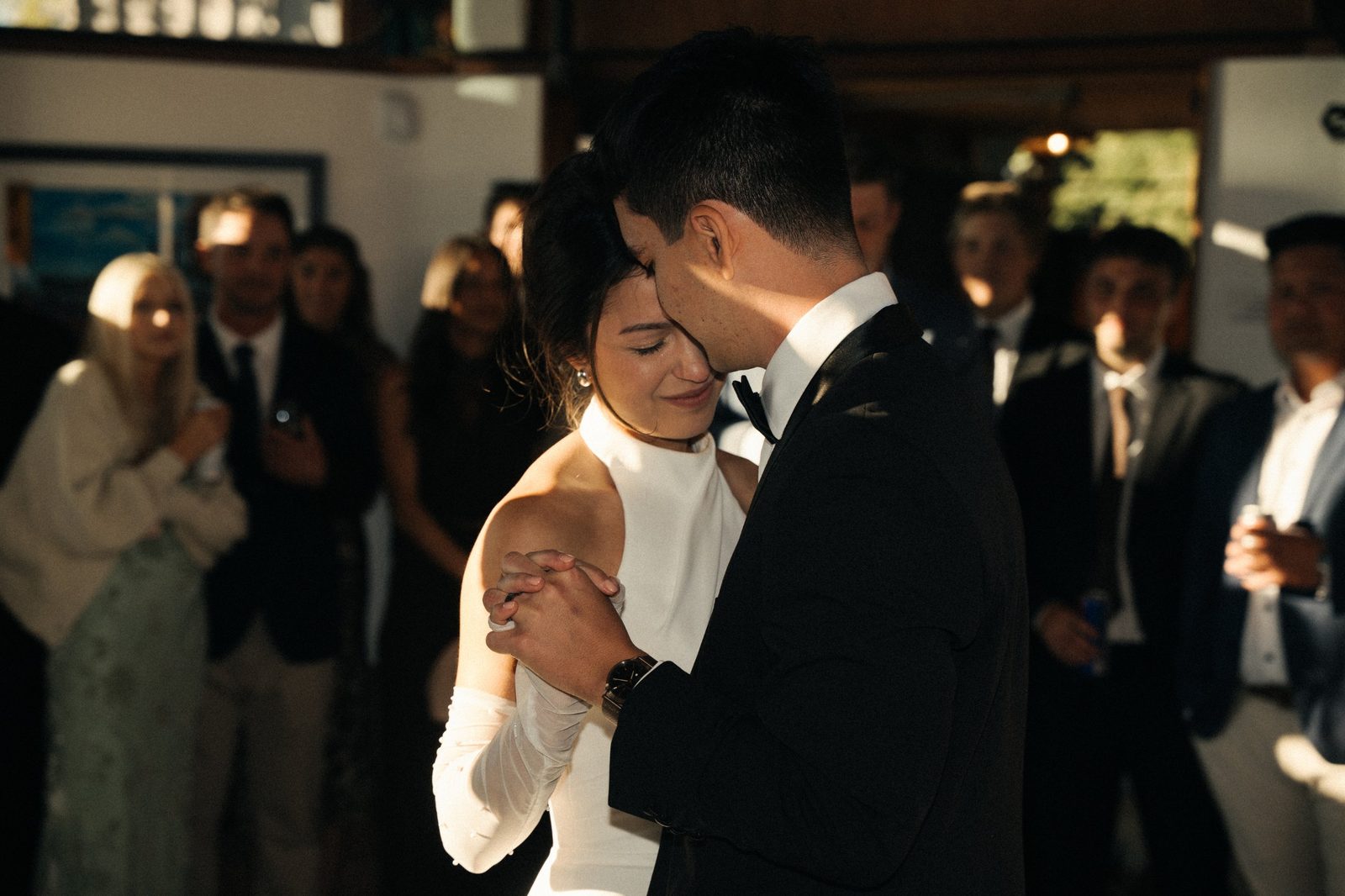Becca and Skyler in their first dance, forehead to forehead, with guests watching behind them